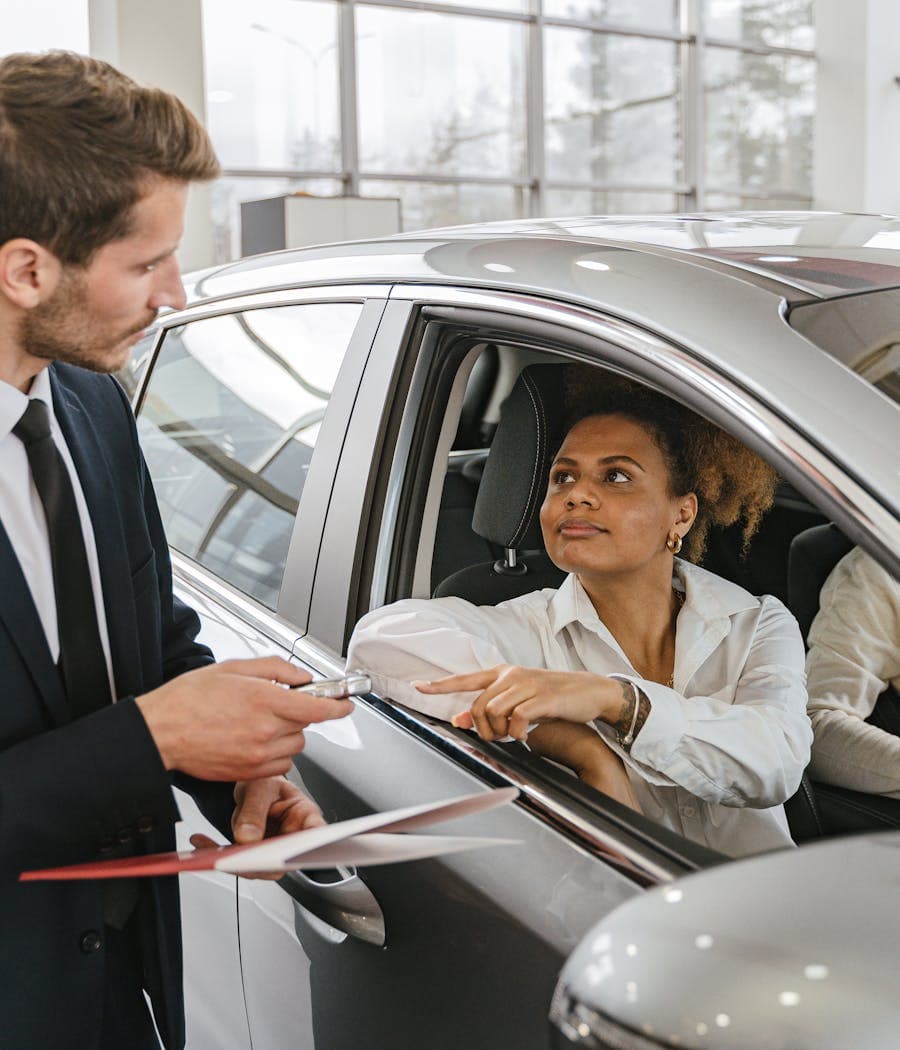 A DriveMatch specialist handing car keys to a happy customer in her new car